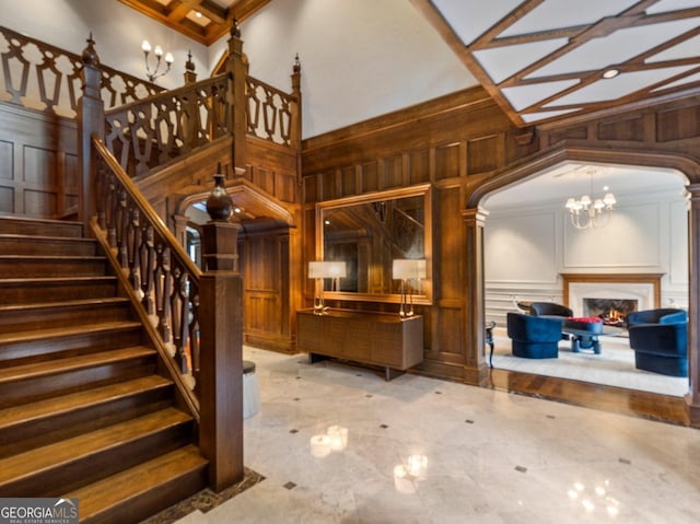 stairs with coffered ceiling, a high ceiling, a chandelier, crown molding, and beam ceiling