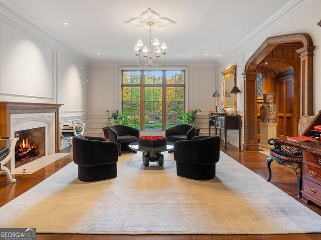 living room with a high end fireplace, crown molding, a notable chandelier, and hardwood / wood-style flooring