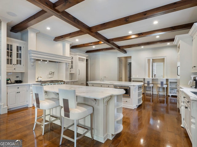 kitchen with stainless steel microwave, dark hardwood / wood-style floors, white cabinets, and a spacious island