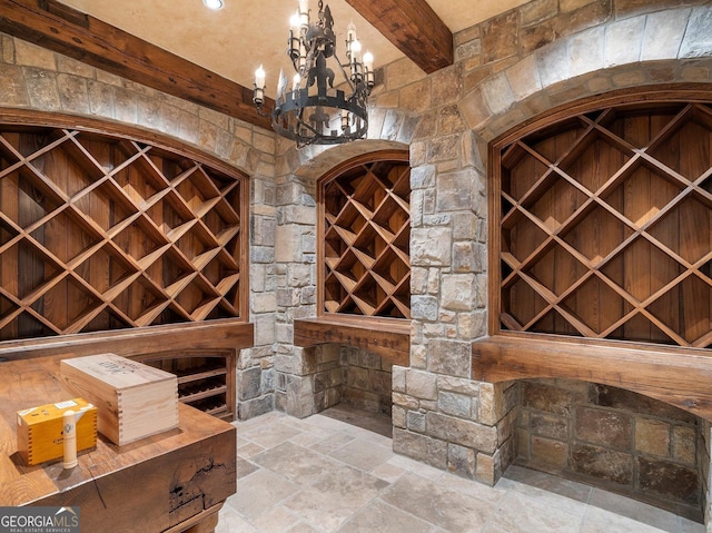 wine area featuring beam ceiling, built in features, and a chandelier