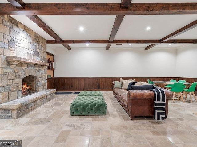 living room with beamed ceiling, a stone fireplace, and wooden walls