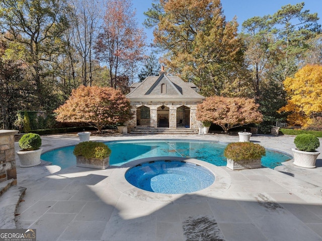 view of pool with a patio area, an outdoor structure, and an in ground hot tub