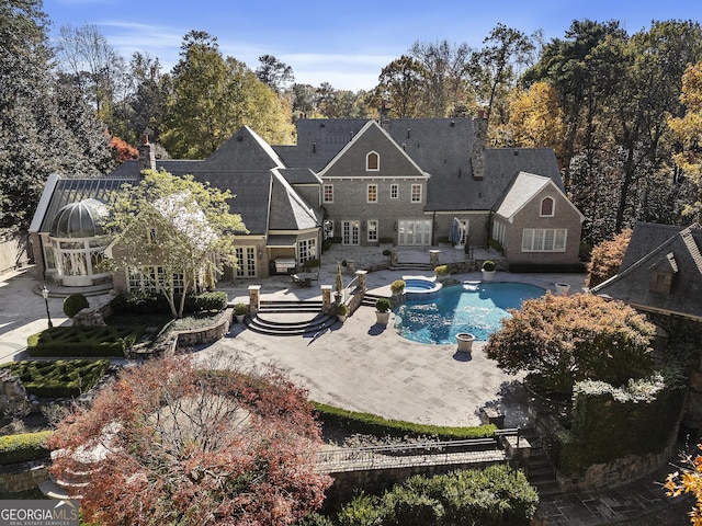 back of property featuring a patio area and a swimming pool with hot tub