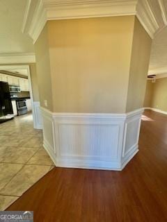 corridor with ornamental molding and hardwood / wood-style floors