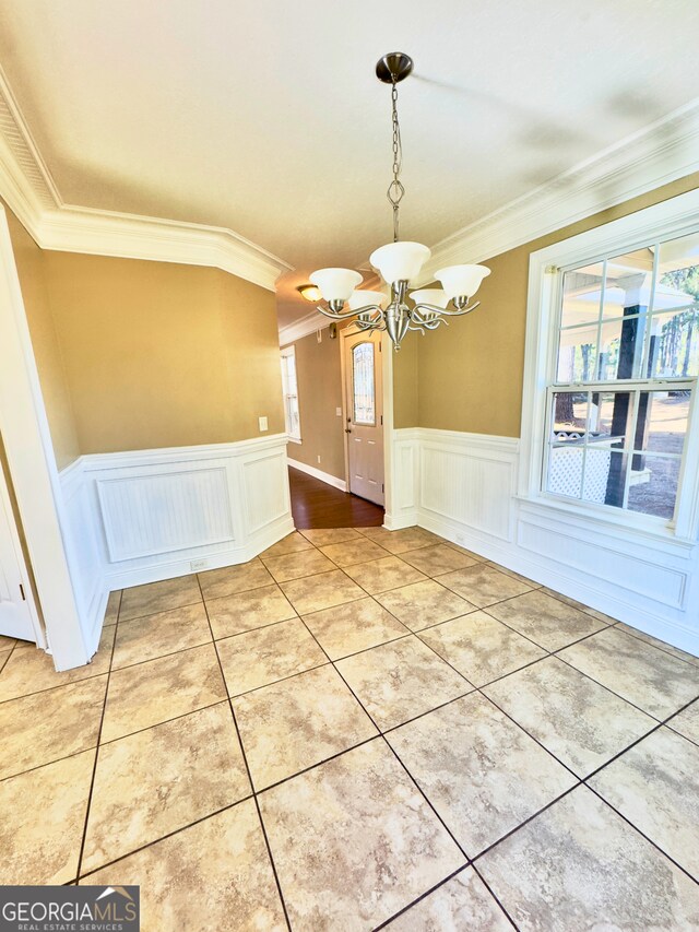 unfurnished dining area with tile patterned flooring, a notable chandelier, and crown molding