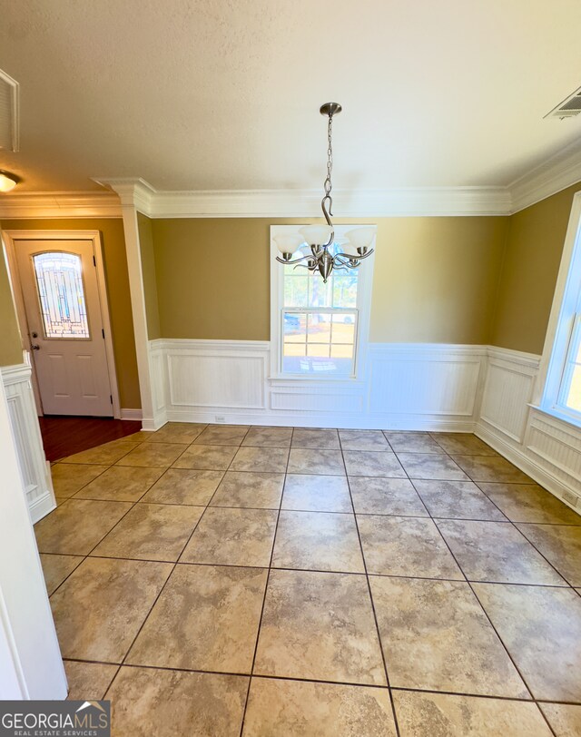 unfurnished dining area featuring an inviting chandelier, ornamental molding, and plenty of natural light