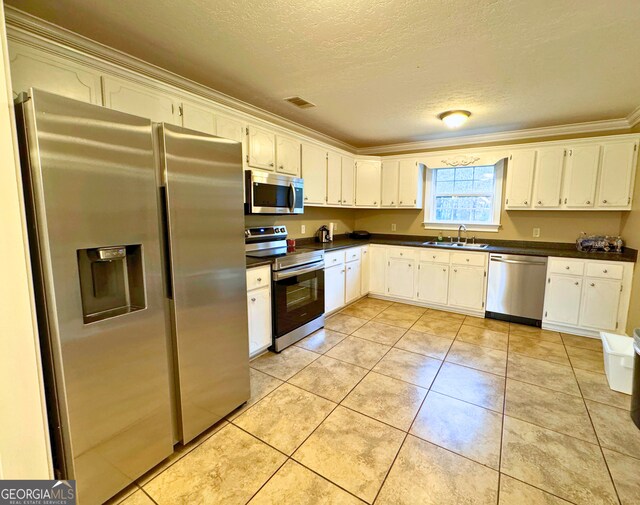 kitchen featuring light tile patterned floors, appliances with stainless steel finishes, ornamental molding, and white cabinetry