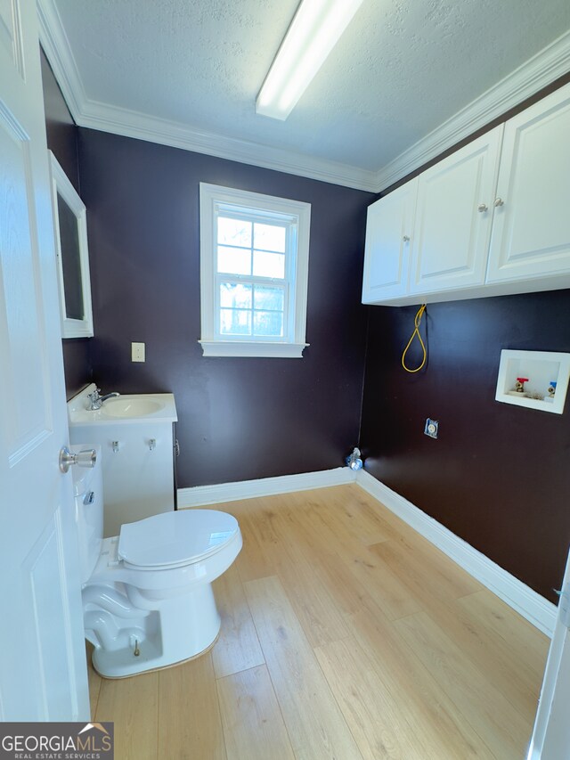 bathroom featuring toilet, ornamental molding, hardwood / wood-style flooring, and sink