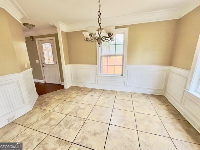 unfurnished dining area featuring crown molding and a notable chandelier