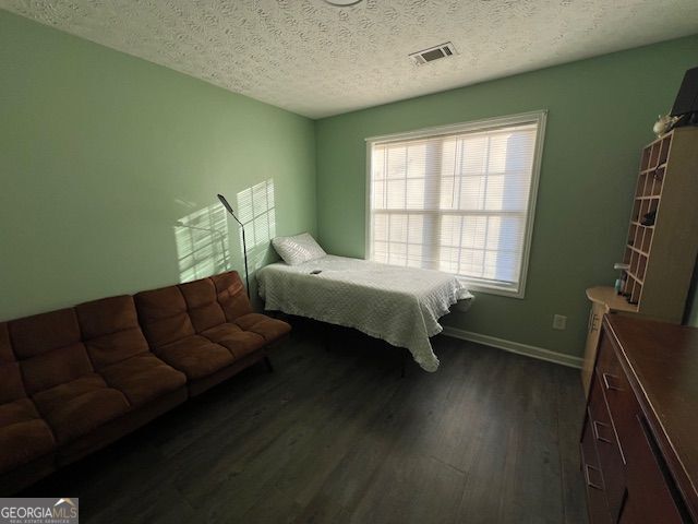 bedroom featuring a textured ceiling, dark hardwood / wood-style floors, and multiple windows