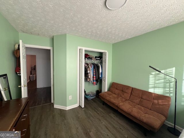 sitting room with dark wood-type flooring and a textured ceiling