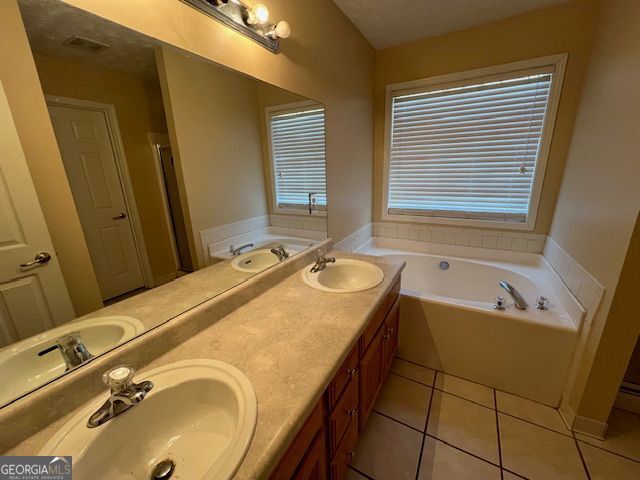 bathroom featuring tile patterned floors, a bathtub, vanity, and a textured ceiling