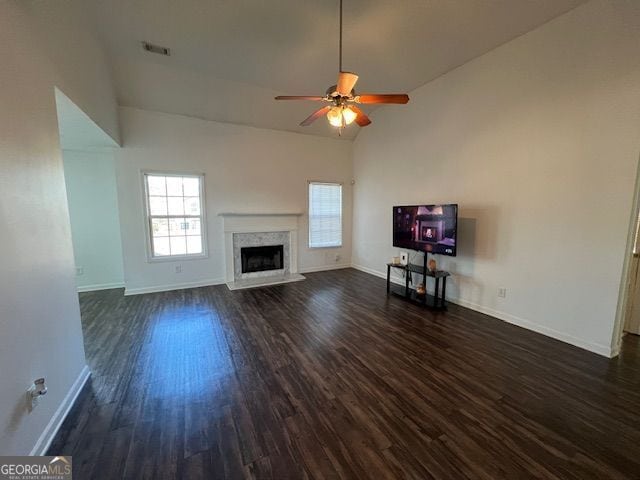 unfurnished living room with ceiling fan, a high end fireplace, dark hardwood / wood-style flooring, and high vaulted ceiling