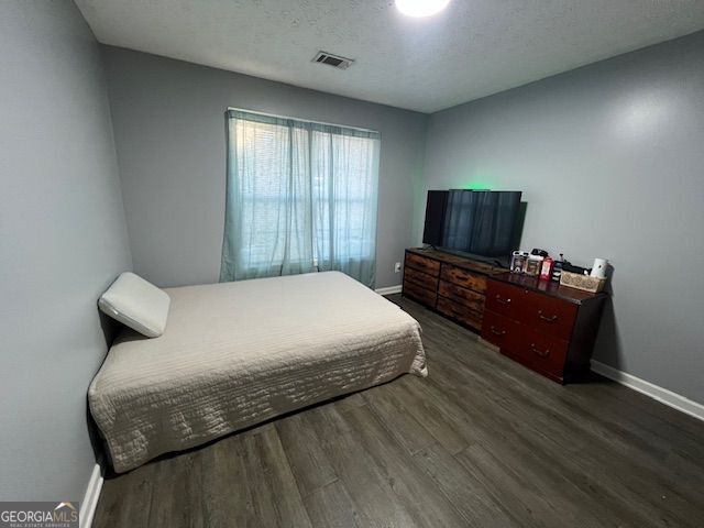 bedroom with a textured ceiling and dark hardwood / wood-style floors