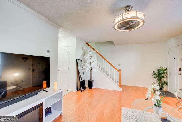 entrance foyer with a textured ceiling, light hardwood / wood-style flooring, and crown molding