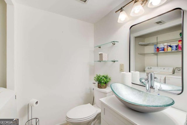 bathroom featuring washing machine and dryer, toilet, and vanity