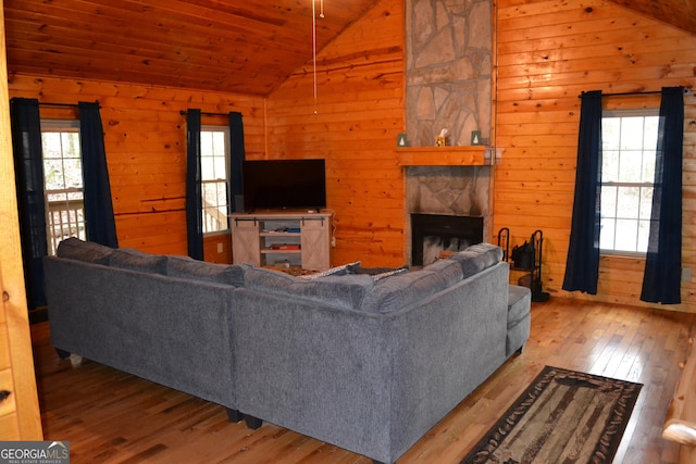 living room featuring vaulted ceiling, a fireplace, a healthy amount of sunlight, wooden ceiling, and light hardwood / wood-style flooring