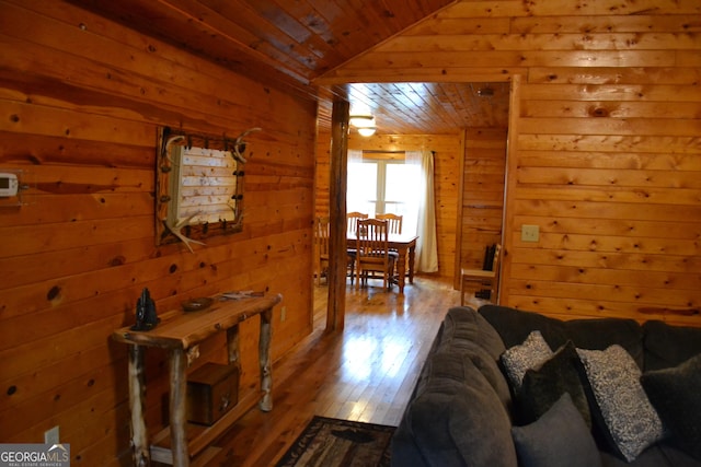 living room featuring lofted ceiling, wood ceiling, wooden walls, and hardwood / wood-style flooring