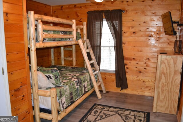 bedroom featuring dark wood-type flooring and wooden walls