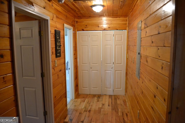 hall featuring wood ceiling, wooden walls, and light wood-type flooring