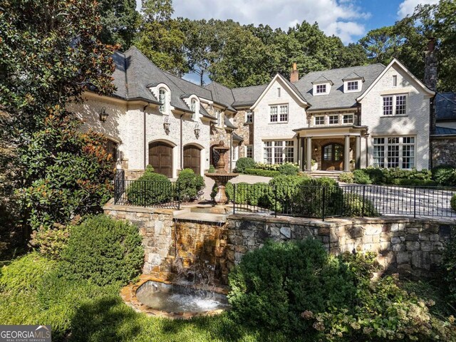 view of front of house featuring stone siding, a chimney, and fence