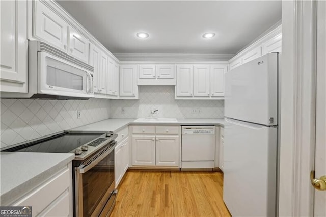 kitchen with white appliances, a sink, light countertops, white cabinetry, and light wood-style floors