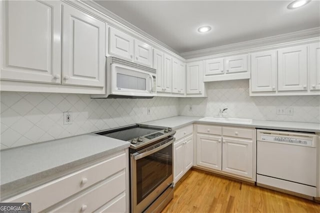 kitchen with white appliances, a sink, light countertops, white cabinetry, and recessed lighting