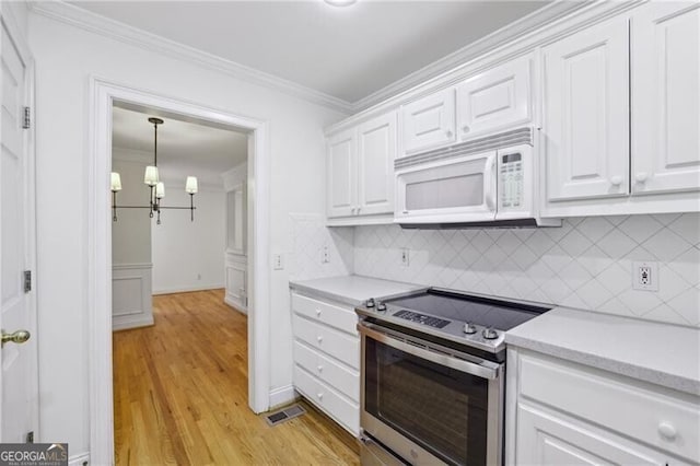 kitchen with stainless steel electric range oven, white microwave, light countertops, crown molding, and white cabinetry