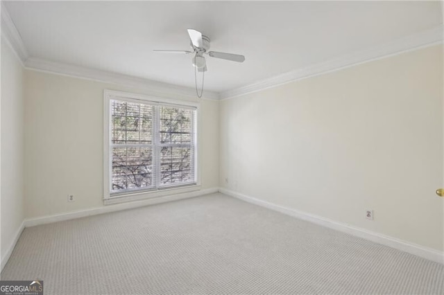 empty room with crown molding, carpet floors, baseboards, and a ceiling fan