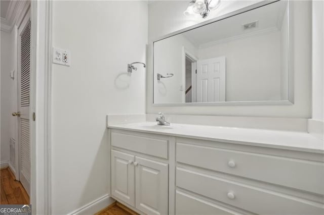 bathroom with vanity, wood finished floors, and crown molding