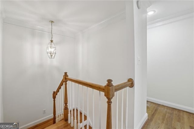 staircase with crown molding, wood finished floors, and baseboards