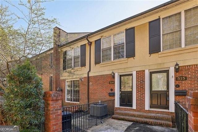 rear view of house featuring entry steps, brick siding, and central AC