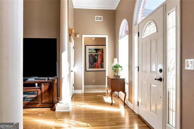 foyer with a high ceiling, light hardwood / wood-style flooring, and decorative columns