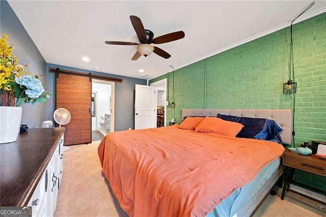 bedroom featuring ceiling fan, a barn door, and ensuite bath