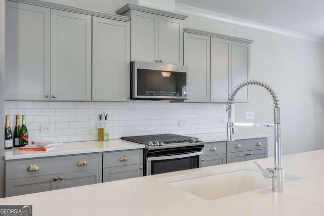 kitchen with sink, backsplash, crown molding, and stainless steel appliances