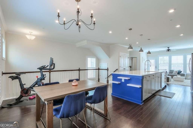 kitchen featuring an island with sink, pendant lighting, crown molding, ceiling fan with notable chandelier, and sink