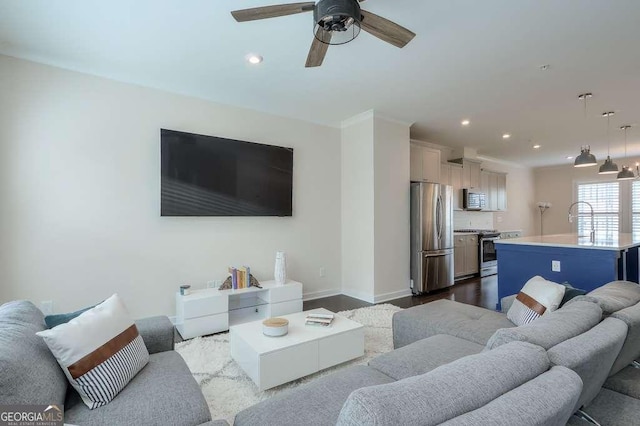 living room with light wood-type flooring, ceiling fan, and sink