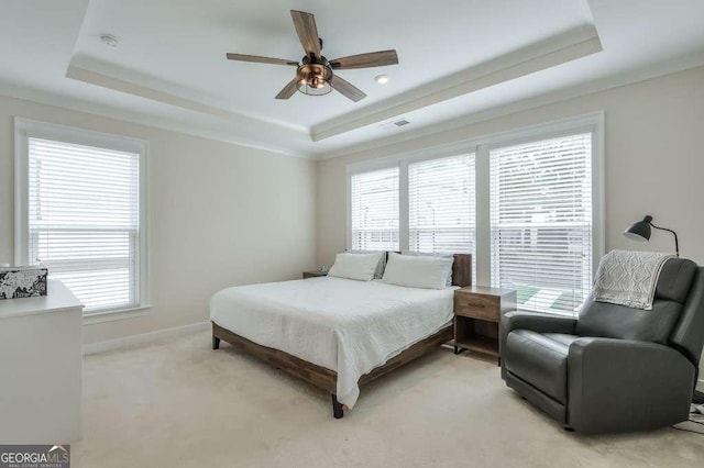 bedroom with ceiling fan, light carpet, a tray ceiling, and multiple windows