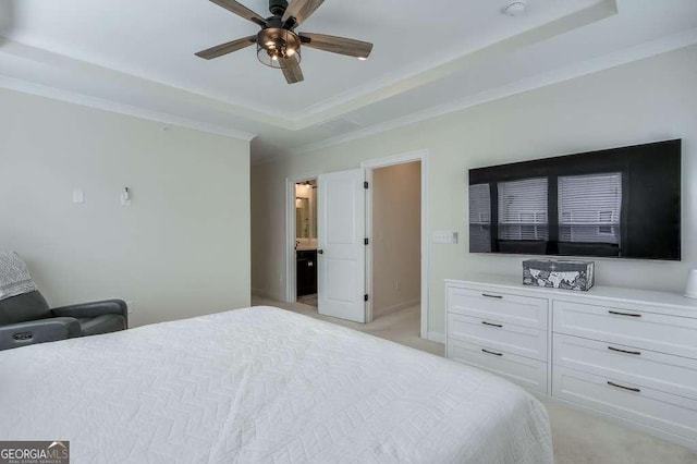 bedroom with ceiling fan, light colored carpet, a tray ceiling, and ensuite bath