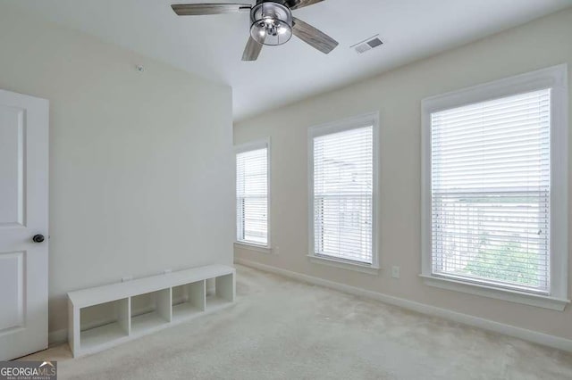 carpeted spare room with ceiling fan and plenty of natural light