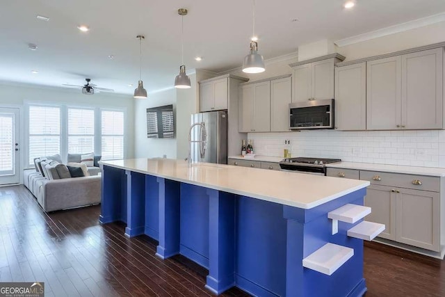 kitchen featuring hanging light fixtures, gray cabinetry, stainless steel appliances, and a center island with sink