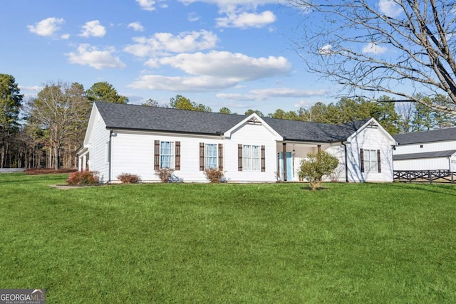 view of front facade featuring a shingled roof and a front yard