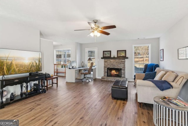 living area featuring ceiling fan, a fireplace, plenty of natural light, and wood finished floors