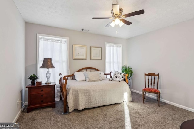 bedroom with carpet, visible vents, a textured ceiling, and baseboards