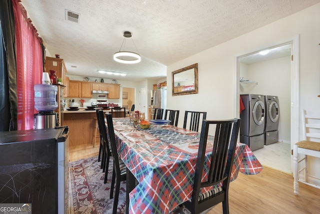 dining area with separate washer and dryer, a textured ceiling, beverage cooler, and light hardwood / wood-style floors