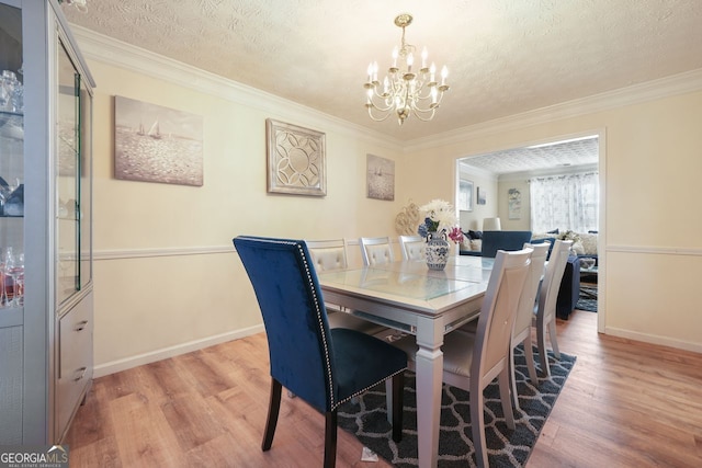 dining area featuring light wood-type flooring, crown molding, and a textured ceiling