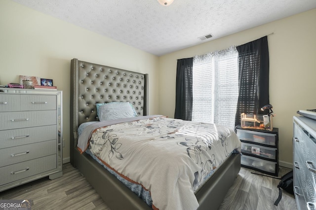 bedroom with a textured ceiling and wood-type flooring