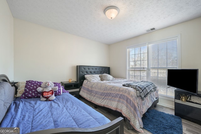 bedroom featuring hardwood / wood-style flooring and a textured ceiling