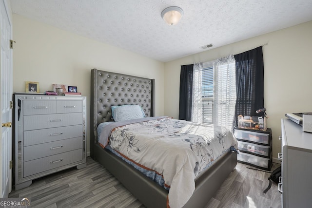 bedroom with a textured ceiling and dark hardwood / wood-style flooring