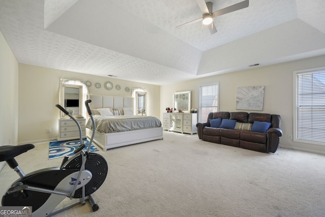 carpeted bedroom with ceiling fan, a raised ceiling, vaulted ceiling, and a textured ceiling